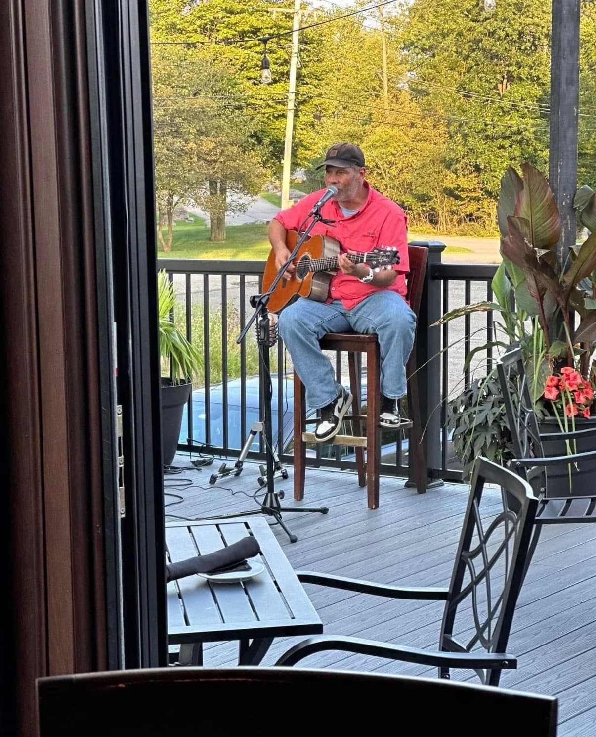 A local artist with an acoustic guitar performing on The Mansard's raised outdoor deck in Orchard Park, NY