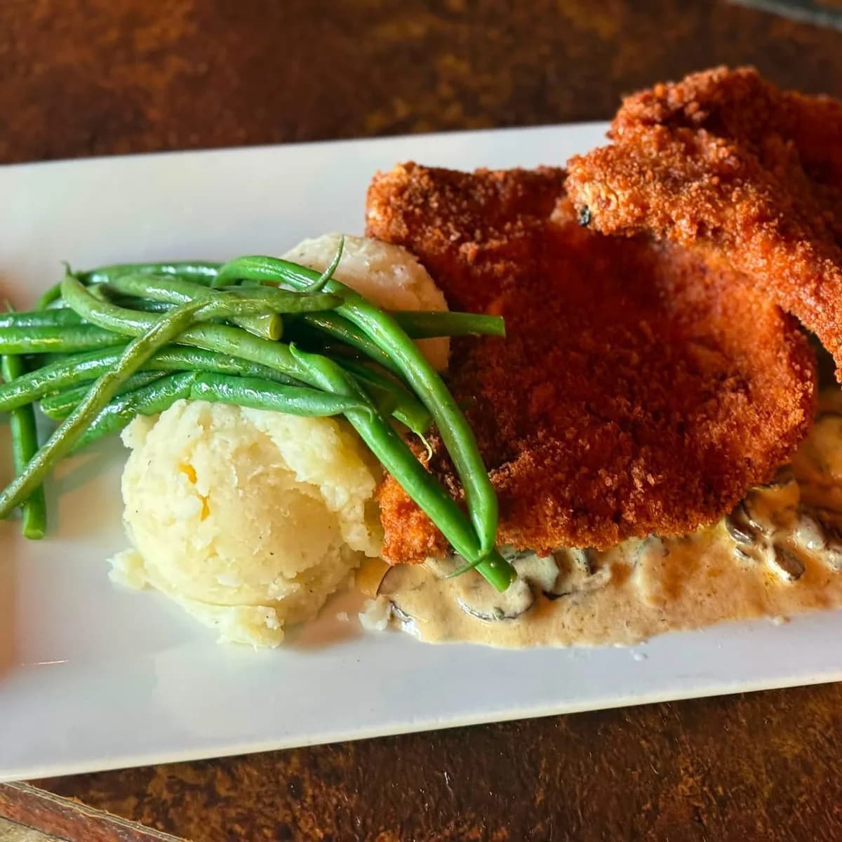 Panko-crusted pork chops over creamed cremini mushrooms with haricot vert and whipped potatoes at The Mansard