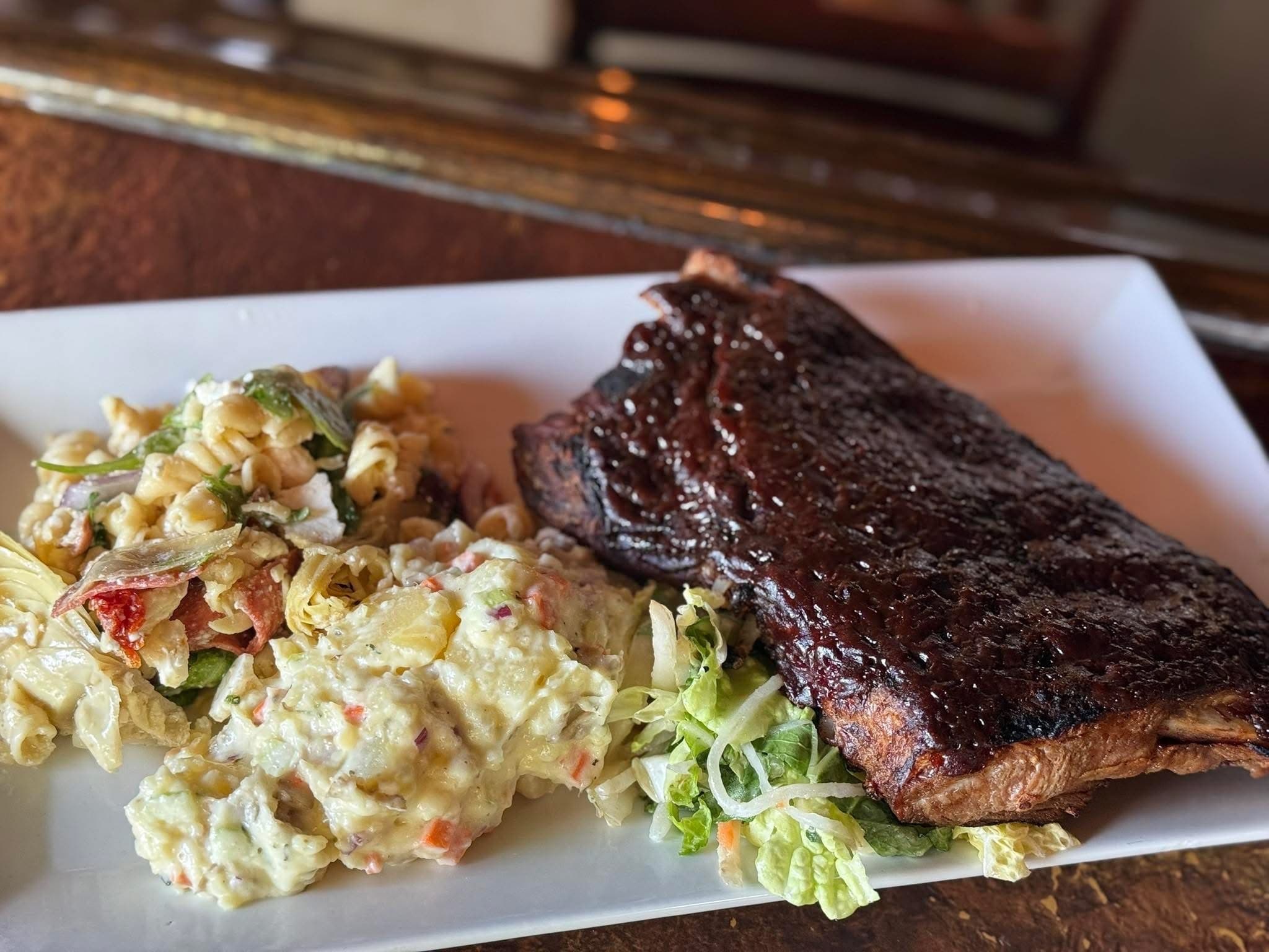 Sous vide spare ribs charbroiled in sweet BBQ sauce, served with potato salad, antipasti salad and shredded vegetable slaw at The Mansard